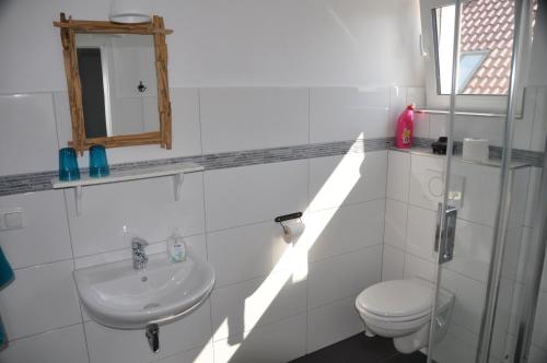 a white bathroom with a sink and a toilet at Hotel & Ferienunterkünfte Hus Seeblick in Fehmarn
