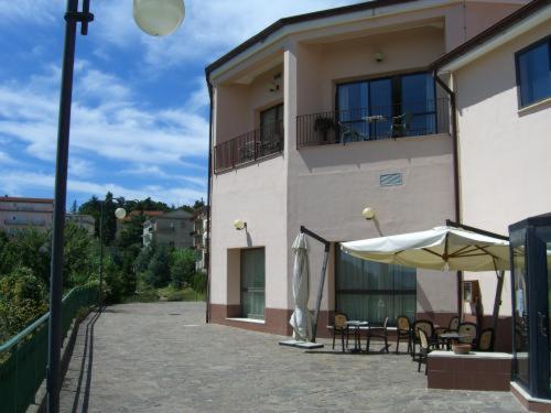 a building with a patio with tables and an umbrella at Hotel Ambasciatori in Calitri