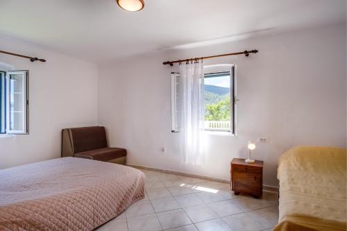 a bedroom with a bed and a window and a chair at Apartments Valun in Valun
