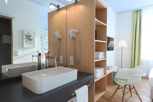 een badkamer met een witte wastafel en een spiegel bij MOMA1890 Boutique Hotel in München