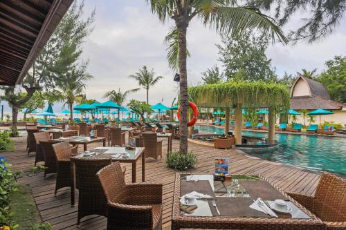 a restaurant with tables and chairs next to a pool at Vila Ombak in Gili Trawangan