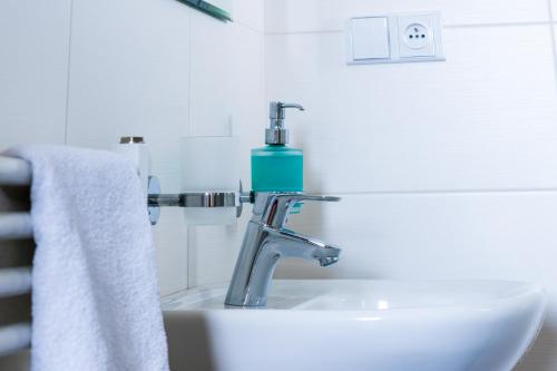 a bathroom sink with a blue soap bottle on it at Restaurace&Rooms Na Jitrách in Semice