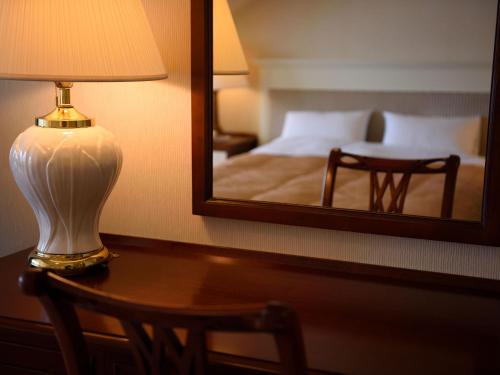 a lamp sitting on a table in front of a mirror at Urabandai Lake Resort Goshiki no Mori in Kitashiobara