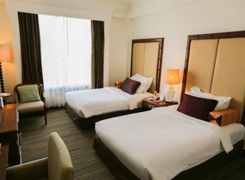 a hotel room with two beds and a chair at The Imperial Hotel & Convention Centre Korat in Nakhon Ratchasima