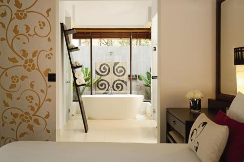 a bathroom with a bath tub in a bedroom at Mövenpick Asara Resort & Spa Hua Hin in Hua Hin