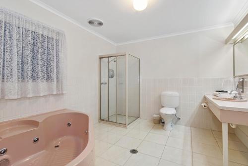 a bathroom with a tub and a toilet and a sink at Golden Square Motor Inn in Bendigo