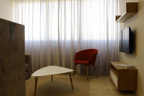 a living room with a red chair and a television at Grey Apartment Lebanon by Grey pearls in Jounieh