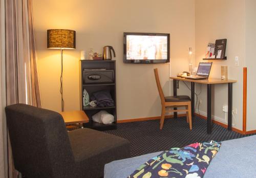 a hotel room with a bed and a desk and a television at Best Western Plus Grand Hotel Elektra in Ludvika