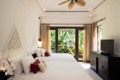 a bedroom with a bed with a television and a window at Mövenpick Asara Resort & Spa Hua Hin in Hua Hin