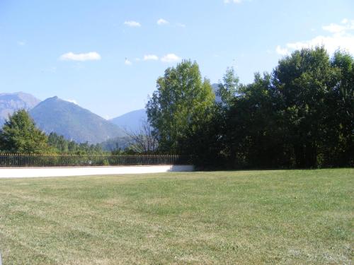 a grassy field with trees and mountains in the background at La Résidence de Lorelei in Cierp
