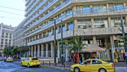 due macchine gialle parcheggiate di fronte a un edificio di Athens Central Apartment ad Atene