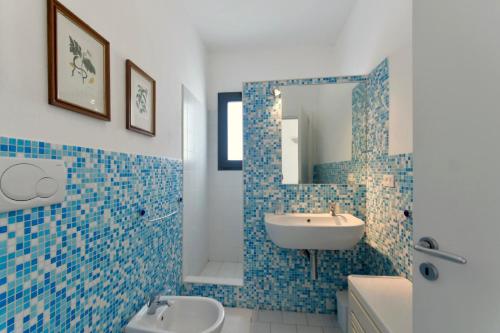 bagno piastrellato blu con lavandino e specchio di Agriresidence Campi Latini a Galatone