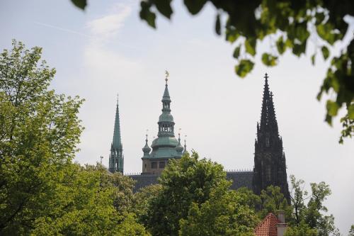 two towers of a building with trees in the foreground at Flamingo Apartments in Prague