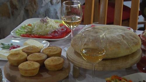 a table with a plate of food and a glass of wine at Motel Lepo Mesto in Strmosten