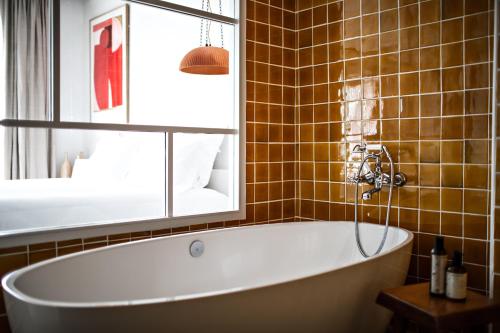 a bath tub in a bathroom with a mirror at Les Roches Rouges, a Beaumier hotel in Saint-Raphaël