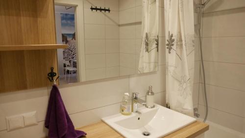 a white bathroom with a sink and a shower at Wieżowiec Ocean Spokojny in Gdańsk