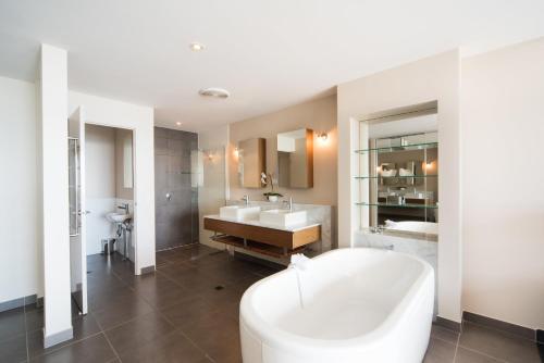 un bagno bianco con vasca e lavandino di Whitsunday Reflections ad Airlie Beach