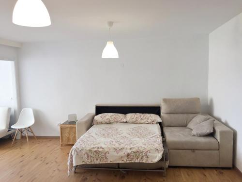 a bed and a couch in a white room at Alteasol playa in Altea