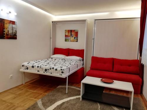 een kleine kamer met een bed en een rode bank bij Lola 1 in Belgrado