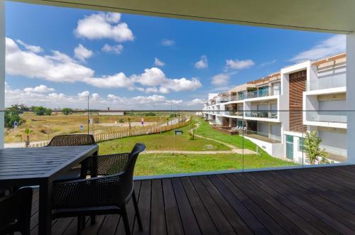 a balcony with a table and chairs and a large window at Praia do Sal Resort in Alcochete