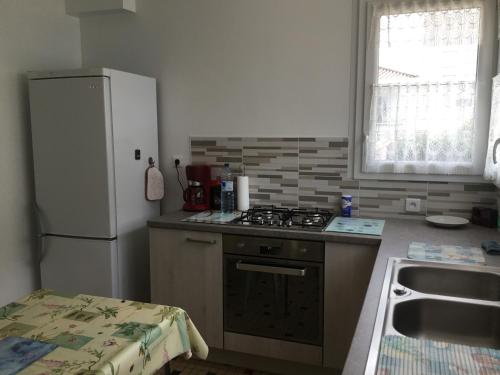 La cuisine est équipée d'un réfrigérateur, d'une cuisinière et d'un évier. dans l'établissement Maison de vacances à St JEAN DE MONTS, à Saint-Jean-de-Monts