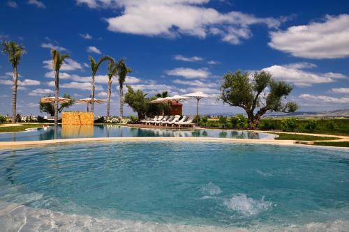 a large swimming pool with chairs and palm trees at Château Roslane Boutique hôtel & Spa in Meknès