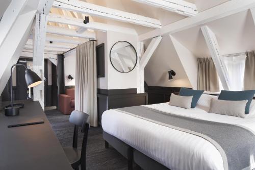 a bedroom with a bed and a desk and a mirror at Hôtel Du Dragon in Strasbourg
