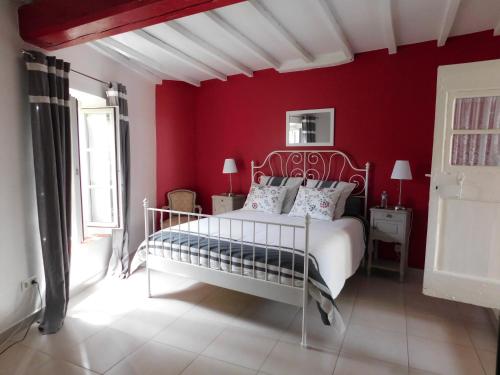 ein Schlafzimmer mit einem weißen Bett in einer roten Wand in der Unterkunft La Maison Jules Goux in Mirmande