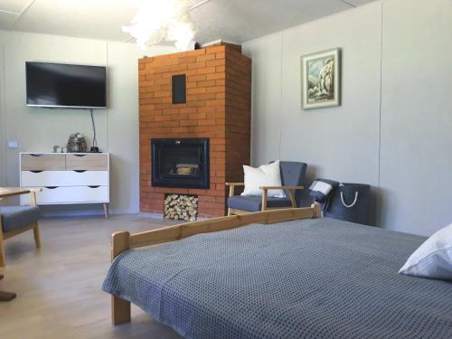 1 dormitorio con 1 cama y chimenea con TV en Atpūtas vieta Brāļtīrumi, en Pūrciems
