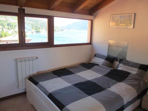 1 Schlafzimmer mit einem schwarzen und weißen Bett und 2 Fenstern in der Unterkunft Apartmentslagodicomo in Acquaseria