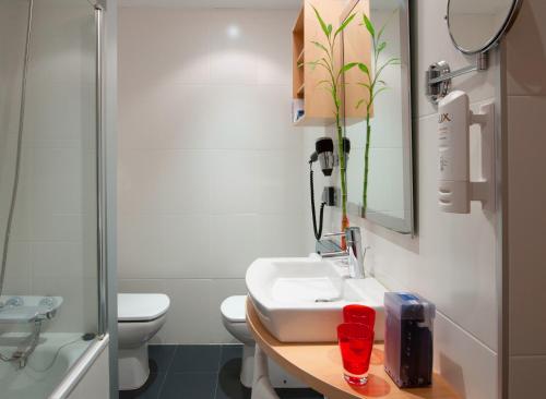 a bathroom with a sink and a toilet and a mirror at Hotel Zentral Ave in Zaragoza