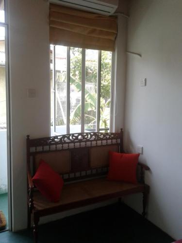 a bench in front of a window with red pillows at Mini's Residence in Colombo