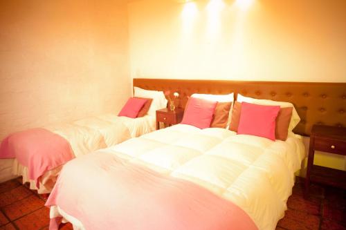 a bedroom with two beds with white and pink pillows at Hotel La Mision in Colonia del Sacramento