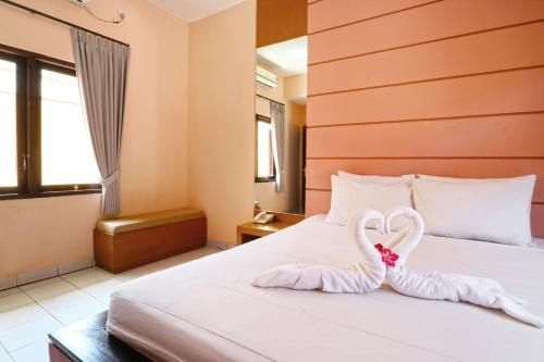 two swans shaped like hearts are sitting on a bed at Sayang Residence I in Denpasar