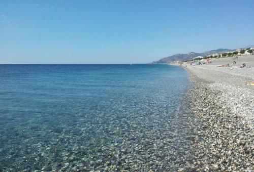 a beach with a rocky shoreline and the ocean at Timone in Roccalumera