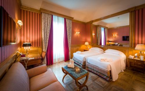 トリノにあるグランド ホテル シテアのベッドとソファ付きのホテルルーム