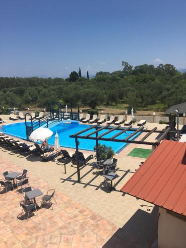 una gran piscina con sillas y una persona sentada en Nikos Villas en Kavos