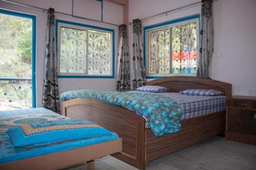 two beds in a bedroom with two windows at Hotel Golden Crown Laxman Jhula in Rishīkesh