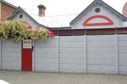 a white building with a red door and a fence at Haus Accommodation - note - Valid passport required to check-in in Perth