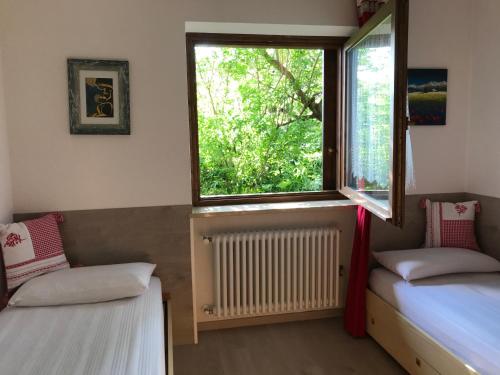 een kamer met 2 bedden, een raam en een radiator bij Almida in Castello di Fiemme