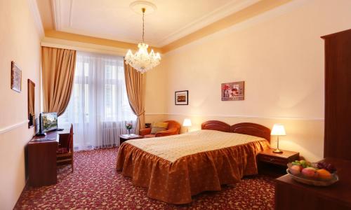 a hotel room with a bed and a chandelier at Spa Hotel Purkyně in Karlovy Vary