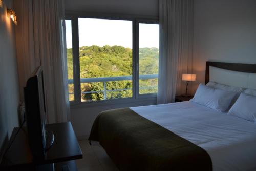 a bedroom with a bed and a large window at Valeria Playa Apart in Valeria del Mar