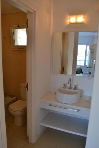 a bathroom with a sink and a toilet and a mirror at Valeria Playa Apart in Valeria del Mar