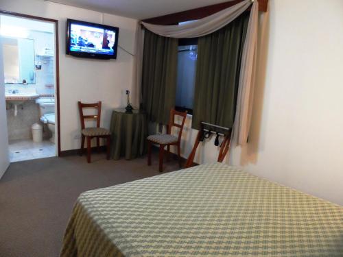 a bedroom with a bed and a table and a television at Intiotel Chiclayo in Chiclayo
