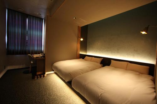 a hotel room with two beds and a desk at Kojohama Onsen Hotel in Shiraoi