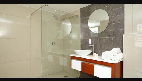 a bathroom with a sink and a shower with a mirror at The Lakes Boutique Lodge in Pretoria