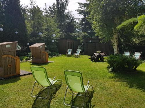 two green chairs sitting in the grass in a yard at 4 STRONY ŚWIATA Pokoje i Apartamenty in Dźwirzyno