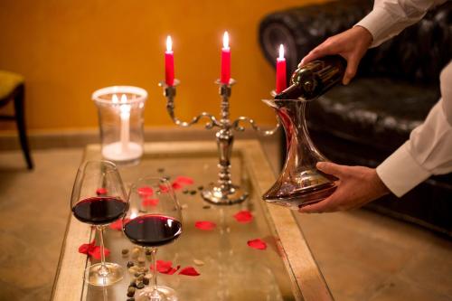 a person pouring wine into a vase on a table with two candles at Agriturismo Il Sapore Della Luna in Monteprandone