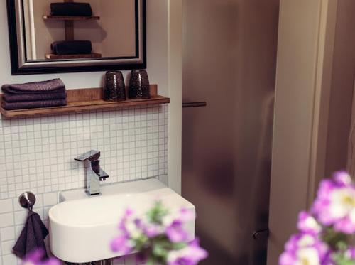 a bathroom with a sink and a mirror and purple flowers at Ambiente Wohnen im Garten in Bad Sobernheim