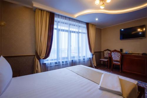 a hotel room with a large bed and a window at Salut Hotel Almaty in Almaty